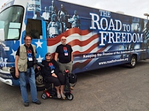 Road to Freedom ADA Bus parked in New Mexico. Tom Olin, Janine Bertram, and Dave Fulton are standing near the driver's window